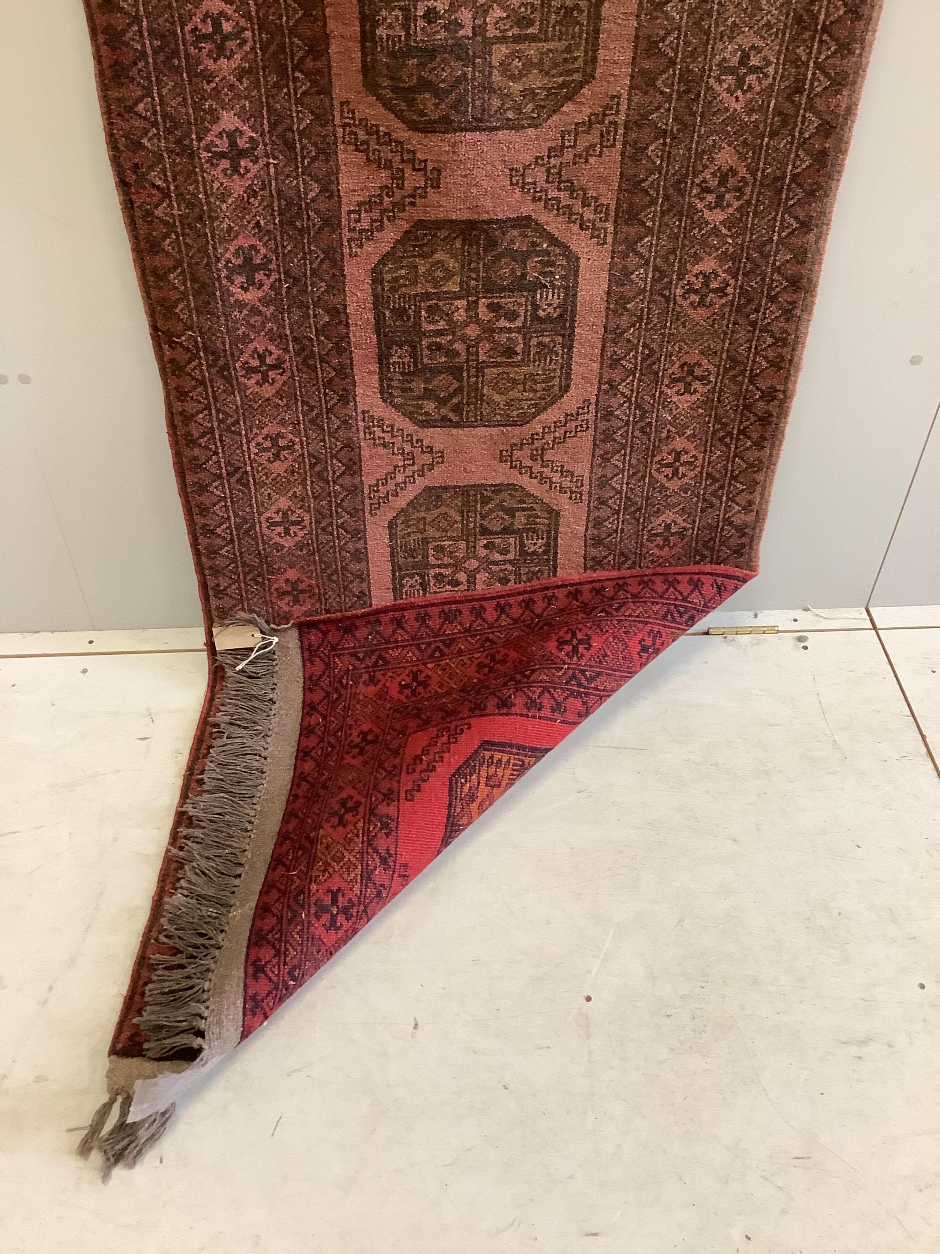 An Afghan red ground runner, 294 x 80cm. Condition - fair